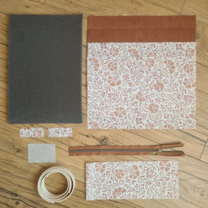 Kit "prêt à coudre" pour réaliser une housse avec anses pour tablette ou iPad en velours côtelé terracotta doublée avec un tissu à motif oriental. Ce kit couture est composé de 2 plaques en mousse, de 2 pièces en velours côtelé terracotta, de 5 pièces en coton imprimé à motif oriental, d'une fermeture éclair marron et de 2 sangles. La housse est personnalisable avec un prénom ou une inscription qui peut être floquée sur une étiquette en tissu coton et lin.