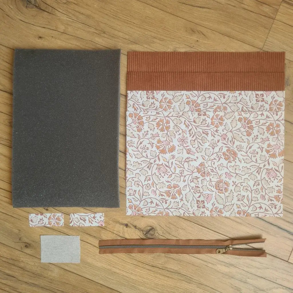 Kit "prêt à coudre" pour réaliser une housse pour tablette ou iPad en velours côtelé marron doublée avec un tissu à motif oriental. Ce kit couture est composé de 2 plaques en mousse, de 2 pièces en velours côtelé marron, de 5 pièces en coton imprimé à motif oriental et d'une fermeture éclair marron. La housse est personnalisable avec un prénom ou une inscription qui peut être floquée sur une étiquette en tissu coton et lin.