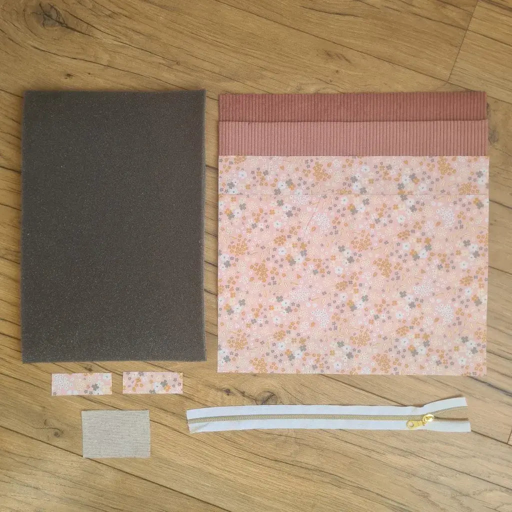 Kit "prêt à coudre" pour réaliser une housse pour tablette ou iPad en velours côtelé rose doublée avec un tissu à motif bouquet. Ce kit couture est composé de 2 plaques en mousse, de 2 pièces en velours côtelé rose, de 5 pièces en coton imprimé à motif bouquet et d'une fermeture éclair blanche. La housse est personnalisable avec un prénom ou une inscription qui peut être floquée sur une étiquette en tissu coton et lin.