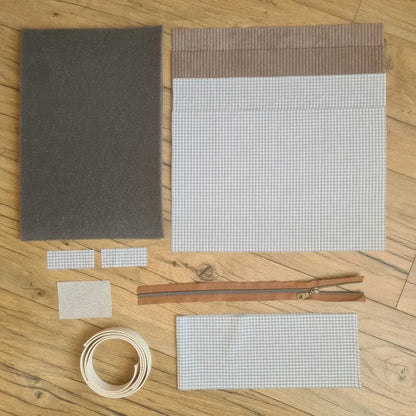 Kit "prêt à coudre" pour réaliser une housse avec anses pour tablette ou iPad en velours côtelé taupe doublée avec un tissu à motif carreaux beiges. Ce kit couture est composé de 2 plaques en mousse, de 2 pièces en velours côtelé taupe, de 5 pièces en coton imprimé à motif carreaux beiges, d'une fermeture éclair marron et de 2 sangles. La housse est personnalisable avec un prénom ou une inscription qui peut être floquée sur une étiquette en tissu coton et lin.