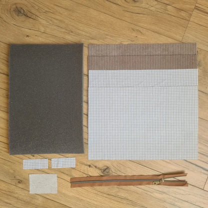 Kit "prêt à coudre" pour réaliser une housse pour tablette ou iPad en velours côtelé taupe doublée avec un tissu à motif carreaux beiges. Ce kit couture est composé de 2 plaques en mousse, de 2 pièces en velours côtelé taupe, de 5 pièces en coton imprimé à motif carreaux beiges et d'une fermeture éclair marron. La housse est personnalisable avec un prénom ou une inscription qui peut être floquée sur une étiquette en tissu coton et lin.