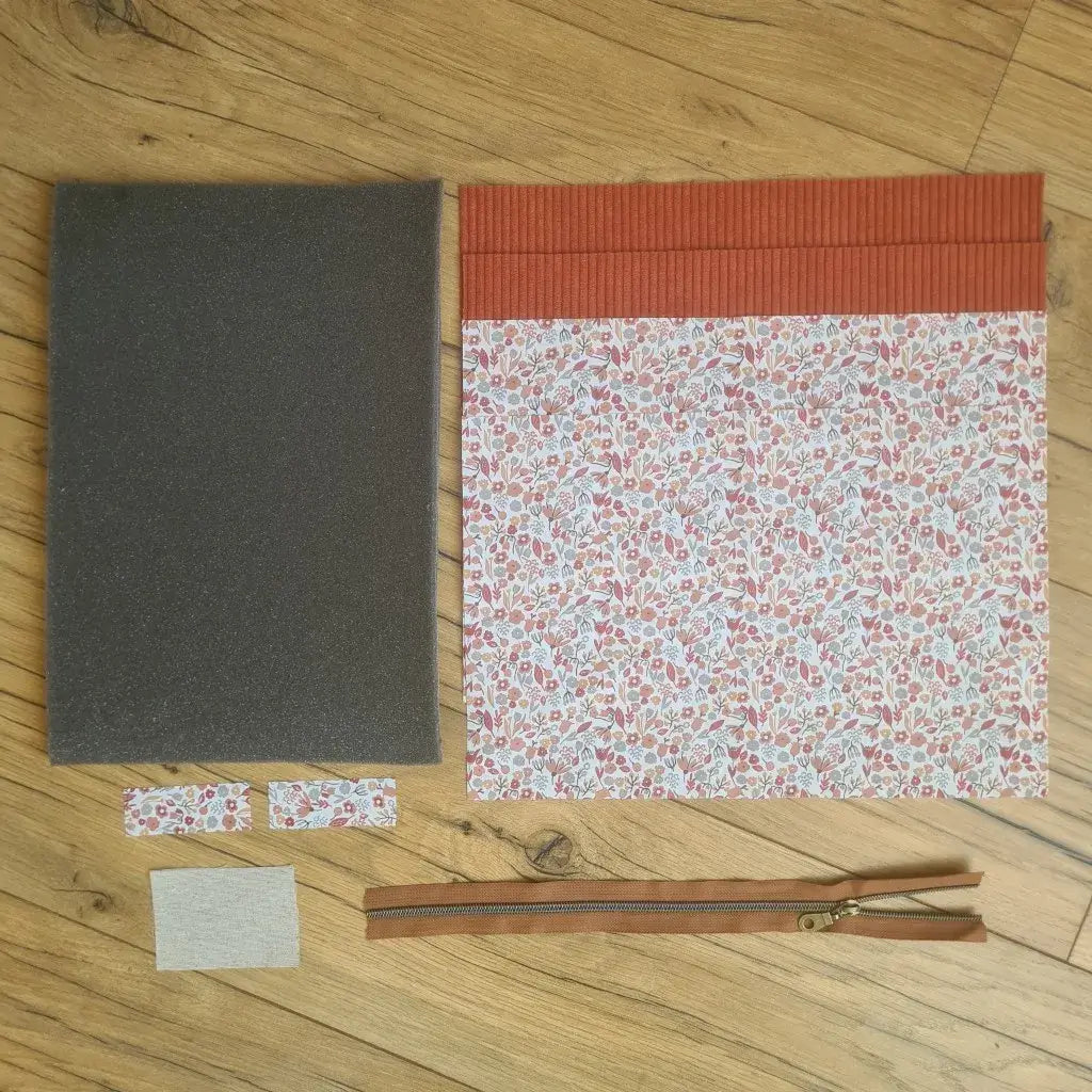 Kit "prêt à coudre" pour réaliser une housse pour tablette ou iPad en velours côtelé terracotta doublée avec un tissu à motif liberty. Ce kit couture est composé de 2 plaques en mousse, de 2 pièces en velours côtelé terracotta, de 5 pièces en coton imprimé à motif liberty et d'une fermeture éclair marron. La housse est personnalisable avec un prénom ou une inscription qui peut être floquée sur une étiquette en tissu coton et lin.