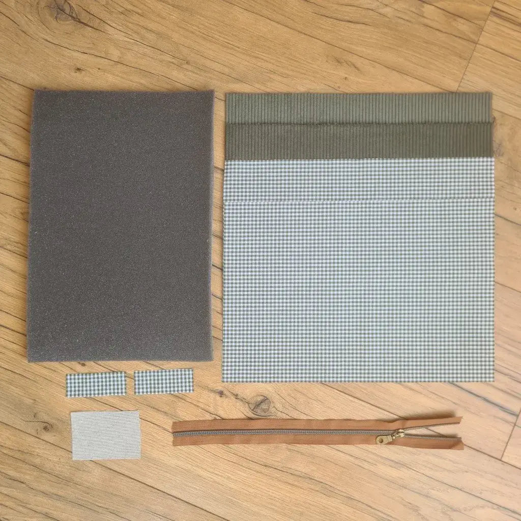 Kit "prêt à coudre" pour réaliser une housse pour tablette ou iPad en velours côtelé vert doublée avec un tissu à motif carreaux verts. Ce kit couture est composé de 2 plaques en mousse, de 2 pièces en velours côtelé vert, de 4 pièces en coton imprimé à motif carreaux verts et d'une fermeture éclair marron. La housse est personnalisable avec un prénom ou une inscription qui peut être floquée sur une étiquette en tissu coton et lin.