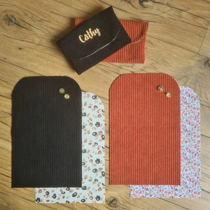 Kit "prêt à coudre" pour réaliser 2 pochettes aimantées en velours côtelé doublées avec un tissu imprimé à motif. Les modèles présentés ici sont pour réaliser une pochette en velours côtelé de coloris noir avec une doublure à motif léopard. La seconde pochette est en velours terracotta avec une doublure au motif liberty. En bas, les pièces de tissus prédécoupées aux bonnes dimensions composant le kit. Au-dessus, les produits finis.
