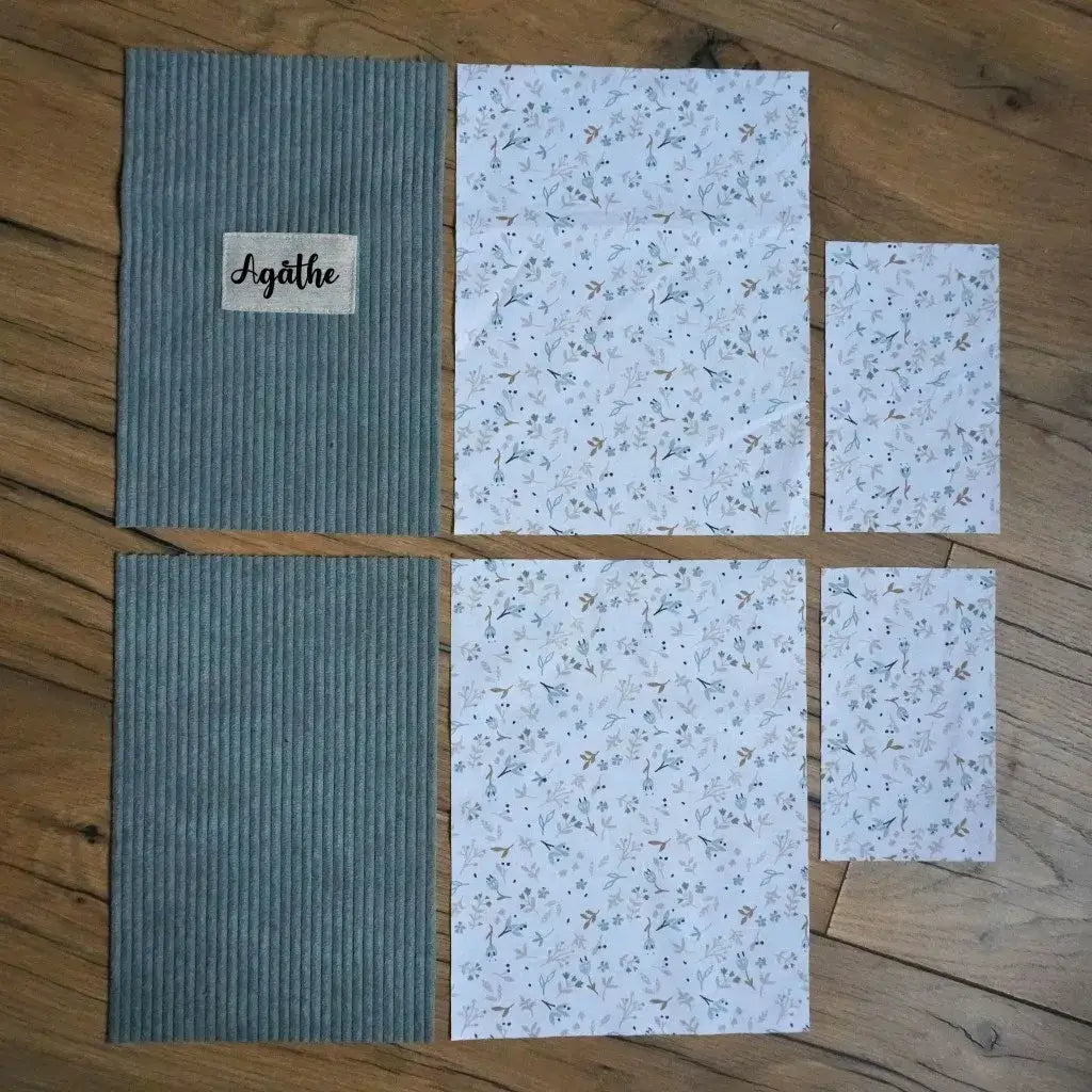 Kit couture à personnaliser : pièces de velours côtelé vert lichen et tissu fleuri assorti posées sur un parquet.