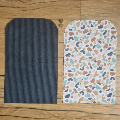 Kit "prêt à coudre" pour une pochette aimantée en velours côtelé au coloris bleu foncé avec une doublure en tissu à motif ptiwi. L'ensemble des pièces de tissu, déjà prédécoupées aux bonnes dimensions, sont disposées au sol. A gauche, une pièce en velours côtelé bleu foncé. A droite, une pièce en tissu imprimé à motif ptiwi. Entre les deux, les 2 pièces composant un bouton aimanté.