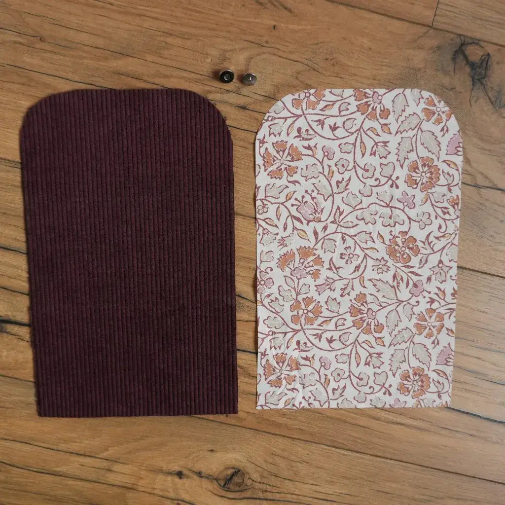Kit prêt-à-coudre pour pochette aimantée composé de deux pièces de tissu : un velours côtelé prune et un coton fleuri oriental dans les tons rose et terracotta, accompagnés de boutons aimantés. Ensemble idéal pour un projet couture DIY simple permettant de réaliser une petite pochette élégante et pratique.