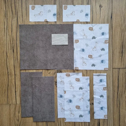 Kit prêt-à-coudre pour protège carnet de santé, composé de tissus prédécoupés en velours côtelé taupe et d’un imprimé savane avec girafes, lions, tortues et éléphants. Accessoire DIY idéal pour confectionner un protège carnet unique et personnalisé. Motif doux et naturel inspiré des animaux de la savane, parfait pour un cadeau de naissance ou pour organiser le carnet de bébé avec une touche originale. Kit complet avec toutes les pièces nécessaires pour une couture facile et un rendu soigné.