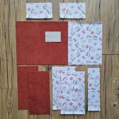 Kit prêt-à-coudre pour protège carnet de santé, composé de tissus prédécoupés en velours côtelé terracotta et d’un imprimé licornes, papillons et fleurs sur fond blanc. Accessoire DIY idéal pour confectionner un protège carnet unique et féerique. Motif enchanteur inspiré de l’univers magique des licornes, parfait pour un cadeau de naissance ou pour organiser le carnet de bébé avec une touche de douceur. Kit complet avec toutes les pièces nécessaires pour une couture facile et un rendu soigné.