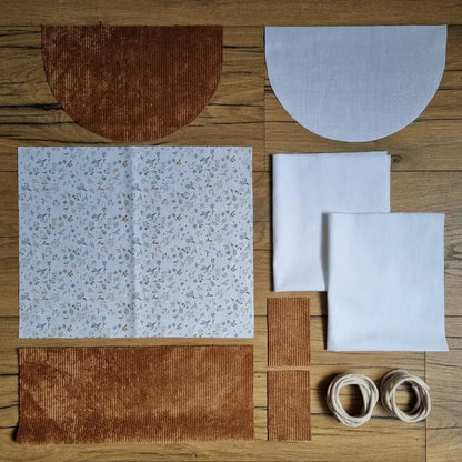 Kit prêt-à-coudre sac à dos pochon avec rabat. Contient : velours côtelé marron, tissu coton motif fleuri 'Azra', doublure blanche, cordons écrus et rabats assortis. Idéal pour un projet couture simple et tendance, parfait pour enfants ou adultes.