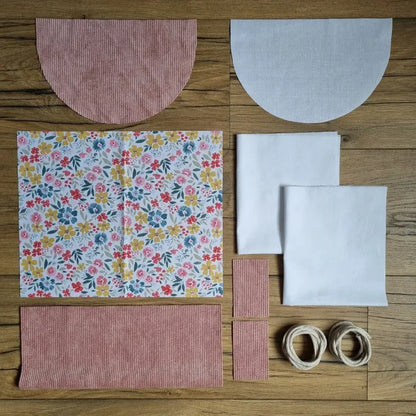 Kit prêt-à-coudre pour sac à dos pochon avec rabat en velours rose : pièces en tissu prédécoupé, imprimé fleuri multicolore, doublure blanche et cordons écrus. Idéal projet couture facile pour débutant.