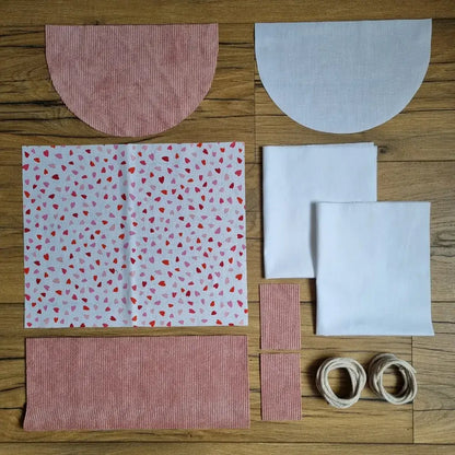 Kit prêt-à-coudre sac à dos pochon avec tissu imprimé petits cœurs rouges et roses, velours côtelé rose poudré, rabat demi-lune assorti et doublure blanche.