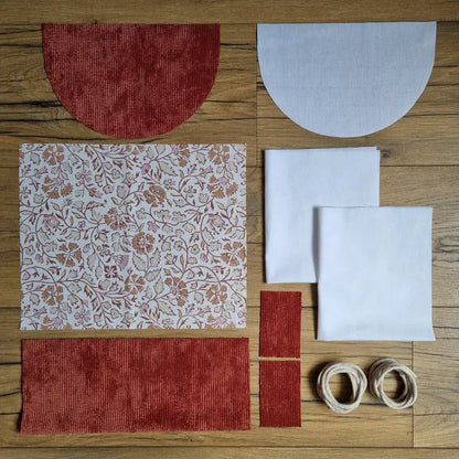 Kit prêt-à-coudre pour sac à dos pochon avec rabat arrondi. Tissus assortis : velours côtelé terracotta, coton à motif oriental et doublure unie. Fournitures incluses : cordons, rabats, panneaux avant/arrière. Parfait pour un projet couture créatif et fait main.