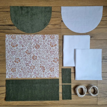Kit prêt-à-coudre pour sac à dos pochon avec rabat arrondi : pièces prédécoupées en velours côtelé vert, tissu coton motif oriental, doublure blanche et cordons écrus. Idéal projet couture DIY pour enfant ou adulte, finition artisanale.