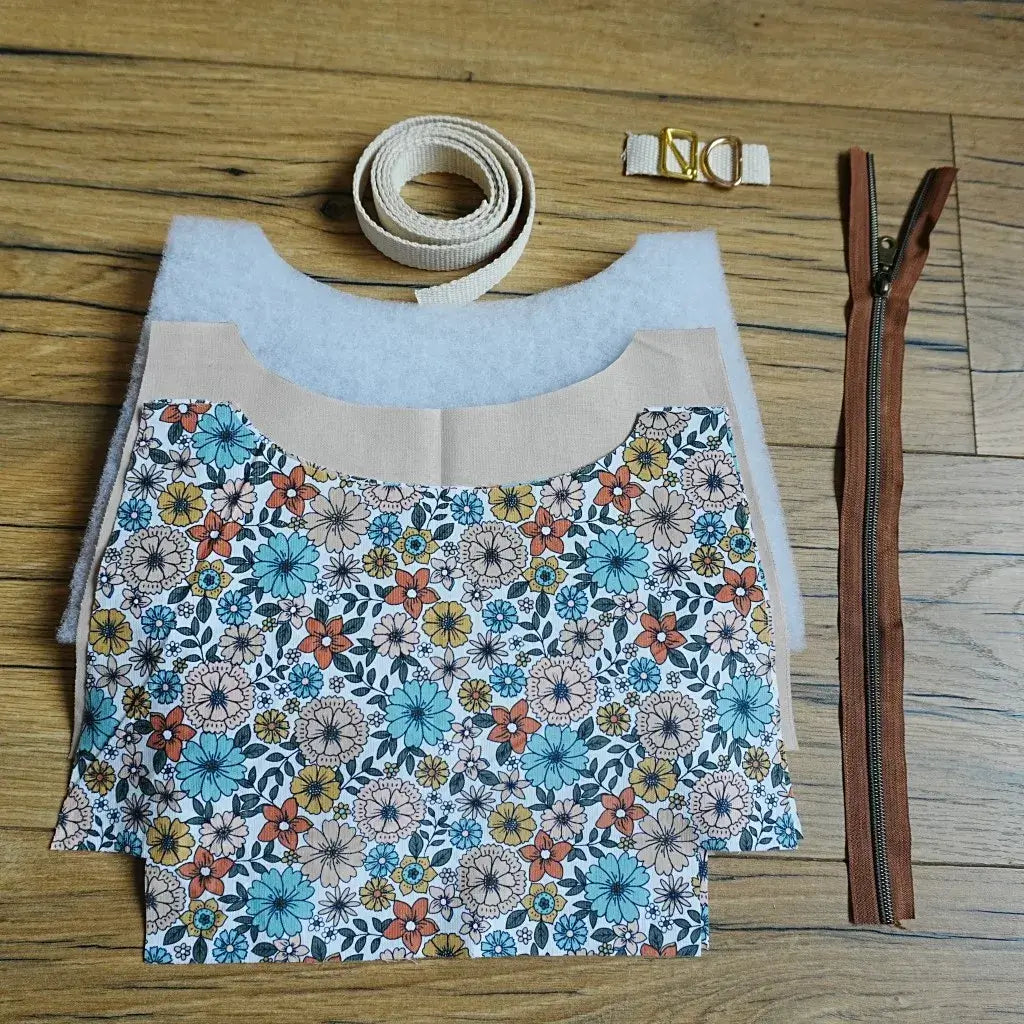 Kit de couture DIY pour sac bandoulière motif fleuri rétro, avec pièces de tissu imprimé aux tons orange, bleu et jaune, sangle en coton beige, fermeture éclair marron et accessoires métalliques. Un ensemble complet pour créer facilement un sac original et tendance, idéal pour les passionnés de couture et les créateurs souhaitant fabriquer un accessoire mode unique et personnalisé.