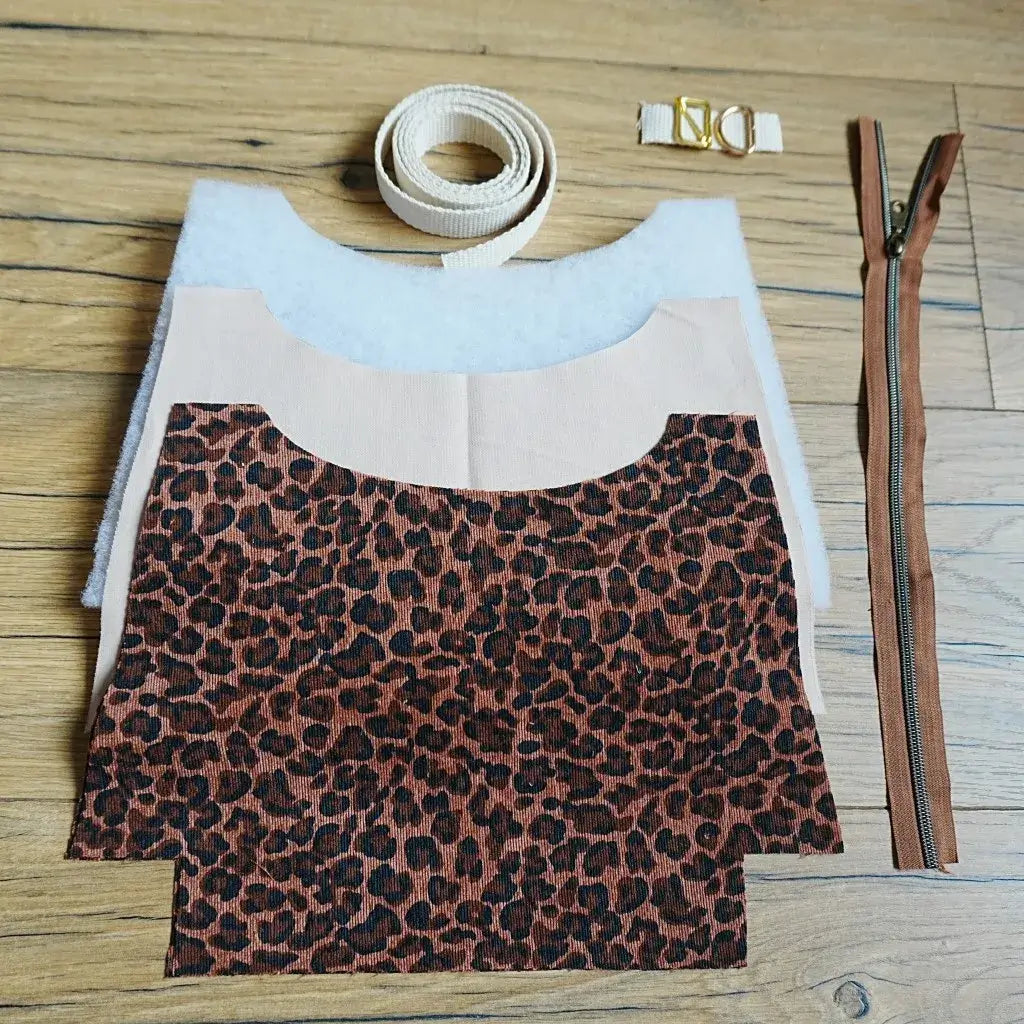 Kit prêt-à-coudre pour sac bandoulière motif léopard marron et noir, comprenant tissu pré-découpé, sangle en coton beige, fermeture éclair marron et boucles métalliques dorées. Ce kit de couture complet permet de fabriquer un sac tendance au style animalier, parfait pour les passionnés de DIY et les débutants souhaitant créer un accessoire mode unique et personnalisé à la main.