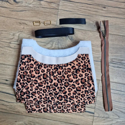 Kit prêt-à-coudre pour sac bandoulière motif léopard marron et noir, comprenant tissu pré-découpé, sangle en coton beige, fermeture éclair marron et boucles métalliques dorées. Ce kit de couture complet permet de fabriquer un sac tendance au style animalier, parfait pour les passionnés de DIY et les débutants souhaitant créer un accessoire mode unique et personnalisé à la main.
