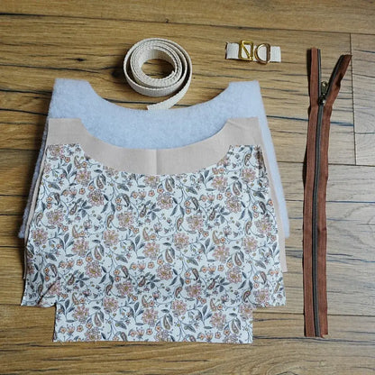 Kit prêt-à-coudre pour sac bandoulière motif fleuri aux tons doux, comprenant tissu imprimé pré-découpé, sangle en coton beige, fermeture éclair marron et boucles métalliques dorées. Idéal pour les amateurs de couture, ce kit complet permet de créer facilement un sac tendance et personnalisé, parfait comme accessoire du quotidien ou comme cadeau fait main unique et élégant.