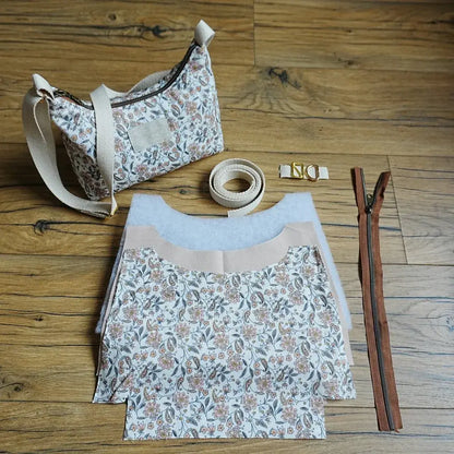 Kit de couture complet pour réaliser un sac bandoulière à motif fleuri, comprenant les pièces de tissu pré-découpées, la sangle en coton beige, une fermeture éclair marron, des boucles métalliques dorées et le sac terminé en exemple. Ensemble idéal pour les passionnés de couture souhaitant confectionner eux-mêmes un sac pratique et tendance, associant créativité et accessoire mode personnalisé.