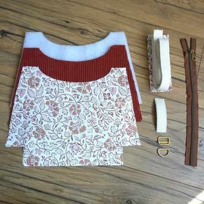 Kit prêt-à-coudre pour sac bandoulière en velours côtelé terracotta et coton imprimé oriental, comprenant pièces de tissu découpées, sangle en coton écru, fermeture éclair marron et boucles métalliques dorées. Ce kit de couture complet permet de réaliser facilement un sac tendance et personnalisé, parfait pour les amateurs de DIY souhaitant créer un accessoire mode unique et fait main.