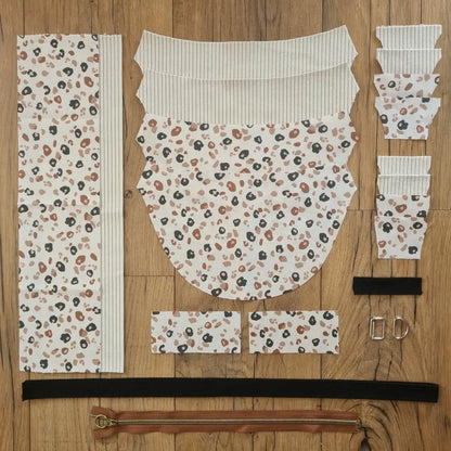 Kit "prêt à coudre" pour un sac demi-lune en velours côtelé au coloris beige avec une doublure en tissu à motif léopard. L'ensemble des pièces de tissu, déjà prédécoupées aux bonnes dimensions, sont disposées au sol et comprennent neuf pièces en tissu à motif léopard et sept pièces en velours côtelé de couleur beige ainsi qu'une fermeture éclair marron et une sangle noire.