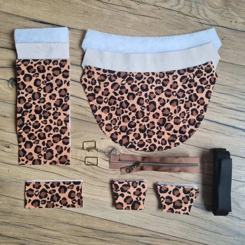 Kit couture sac demi-lune léopard : tissus motif animal, doublure, ouatine, sangle noire et boucles dorées sur bois.