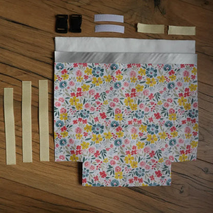 Kit prêt-à-coudre pour sac repas isotherme en coton enduit motif fleuri multicolore, comprenant sangles beige, boucles noires et bandes velcro, idéal pour un projet couture DIY facile et écologique. Permet de fabriquer un lunch bag réutilisable et durable pour l’école, le bureau ou les pique-niques.