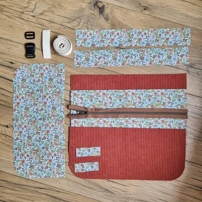 Kit prêt-à-coudre pour tablier ceinture en velours côtelé terracotta et tissu fleuri. Ensemble complet comprenant les pièces de tissu prédécoupées, fermeture éclair marron, sangle écrue et boucles en plastique. Idéal pour un projet couture DIY ou un cadeau fait main.