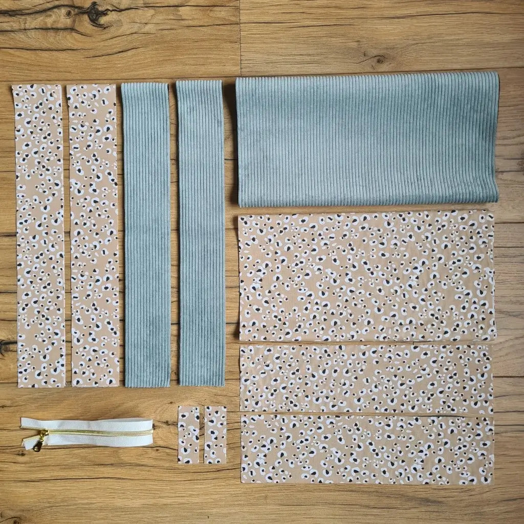 Kit "prêt à coudre" pour un tote-bag en velours côtelé au coloris bleu ciel avec une doublure en tissu à motif léopard. L'ensemble des pièces de tissu, déjà prédécoupées aux bonnes dimensions, sont disposées au sol et comprennent sept pièces en tissu à motif léopard et trois pièces en velours côtelé de couleur bleu ciel ainsi qu'une fermeture éclair blanche.