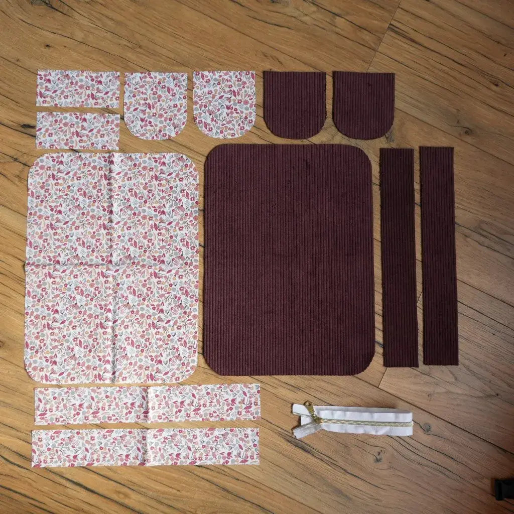 Kit prêt-à-coudre pour trousse de toilette composé de pièces de tissu en velours côtelé prune et coton fleuri type Liberty, avec bandes assorties et fermeture éclair incluse, idéal pour un projet couture DIY facile et élégant. Ensemble de coupons prédécoupés pour créer une trousse de toilette personnalisée faite main.