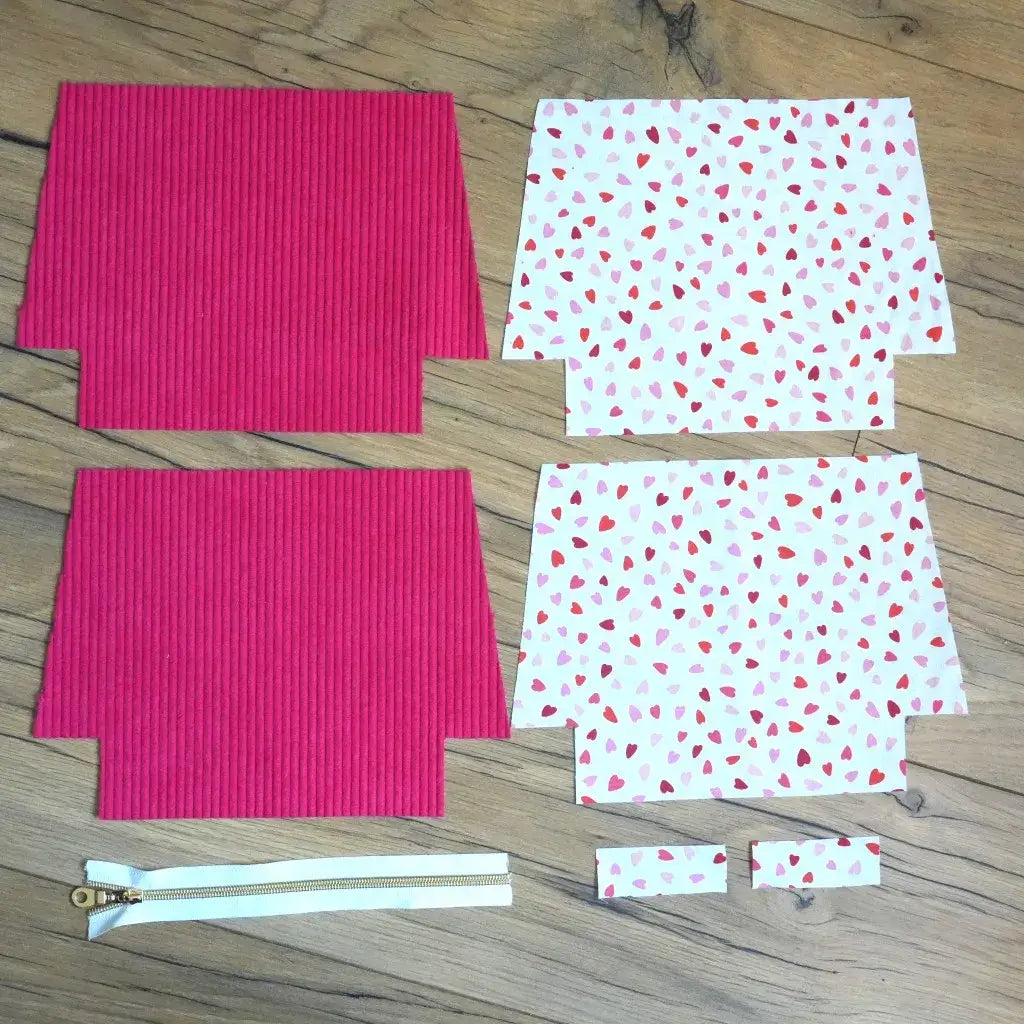 Kit de couture DIY pour réaliser une trousse zippée, composé de pièces de tissu en velours côtelé framboise et coton imprimé cœurs rouges et roses, accompagnées d’une fermeture éclair blanche. Ensemble complet idéal pour débutants et passionnés de couture souhaitant créer une trousse pratique et tendance, parfaite pour ranger accessoires, maquillage ou fournitures, tout en confectionnant un projet fait main unique.