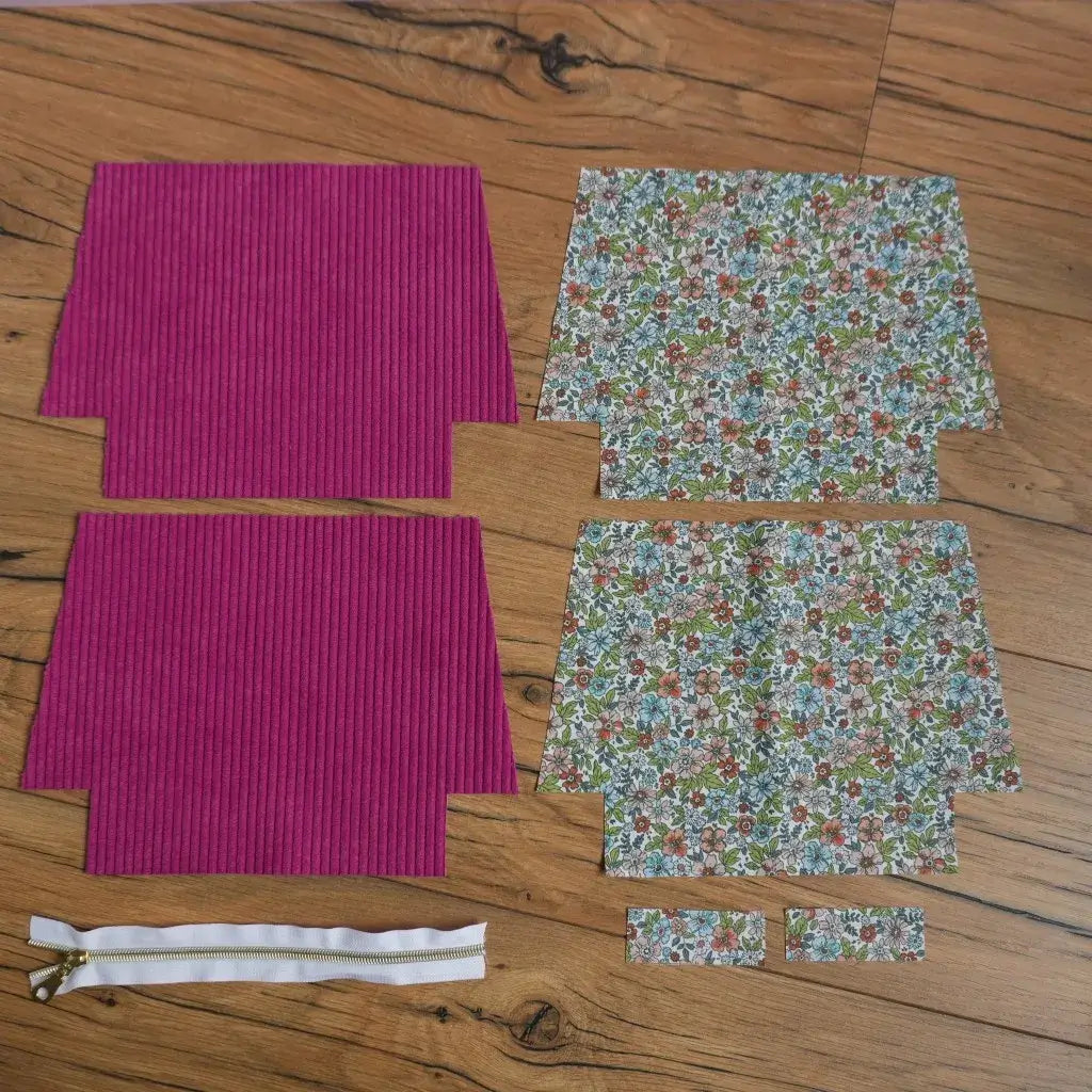 Kit prêt-à-coudre pour trousse zippée en velours côtelé magenta avec doublure en coton fleuri motif pensées, comprenant pièces de tissu prédécoupées et fermeture éclair dorée. Idéal pour un projet couture DIY facile pour fabriquer une trousse personnalisée pour crayons, maquillage ou accessoires.