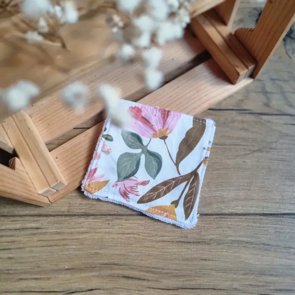 Lingette réutilisable en coton fleuri aux tons automnaux avec motif de feuillage et fleurs roses.