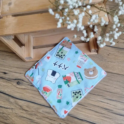 Lingette démaquillante lavable au format maxi 18x18 cm en tissu bleu pastel avec motifs ludiques d’animaux et de gourmandises, posée sur un sol en bois. Accessoire de beauté réutilisable, écologique et zéro déchet, idéal pour une routine de soin respectueuse de l’environnement. Imprimé kawaii avec ourson, pastèques, bonbons et étoiles, apportant une touche joyeuse et enfantine. Fabrication artisanale, couture soignée et texture douce pour un nettoyage du visage tout en délicatesse.