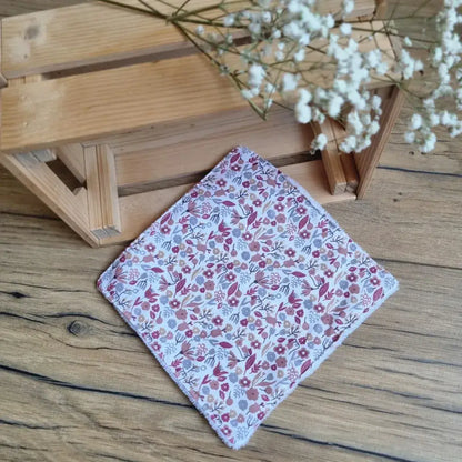 Lingette démaquillante lavable au format maxi 18x18 cm en tissu fleuri, posée sur un sol en bois. Accessoire écologique, réutilisable et zéro déchet, parfait pour une routine beauté responsable. Motif floral délicat aux teintes rouges et roses sur fond blanc, apportant une touche romantique et naturelle. Fabrication artisanale avec couture soignée et texture ultra-douce, idéale pour un nettoyage du visage tout en confort et respect de l’environnement.