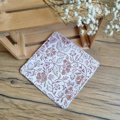 Lingette démaquillante lavable au format maxi 18x18 cm en tissu aux motifs floraux marron sur fond blanc, posée sur un sol en bois. Accessoire de beauté écologique, zéro déchet et réutilisable, idéal pour une routine de soin durable. Design élégant avec imprimé végétal raffiné et typé oriental, couture soignée et texture douce pour un nettoyage du visage en douceur. Fabrication artisanale et respectueuse de l’environnement.