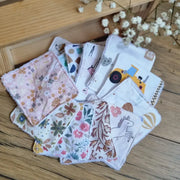 Lot de lingettes démaquillantes lavables en coton imprimé et éponge de bambou, aux motifs variés et colorés, posé sur un sol en bois. Accessoires écologiques, réutilisables et zéro déchet, parfaits pour une routine beauté durable. Ensemble de lingettes aux imprimés adaptés à toutes les préférences. Fabrication artisanale, couture soignée et matière ultra-douce, idéale pour un nettoyage du visage tout en confort et respect de l’environnement.