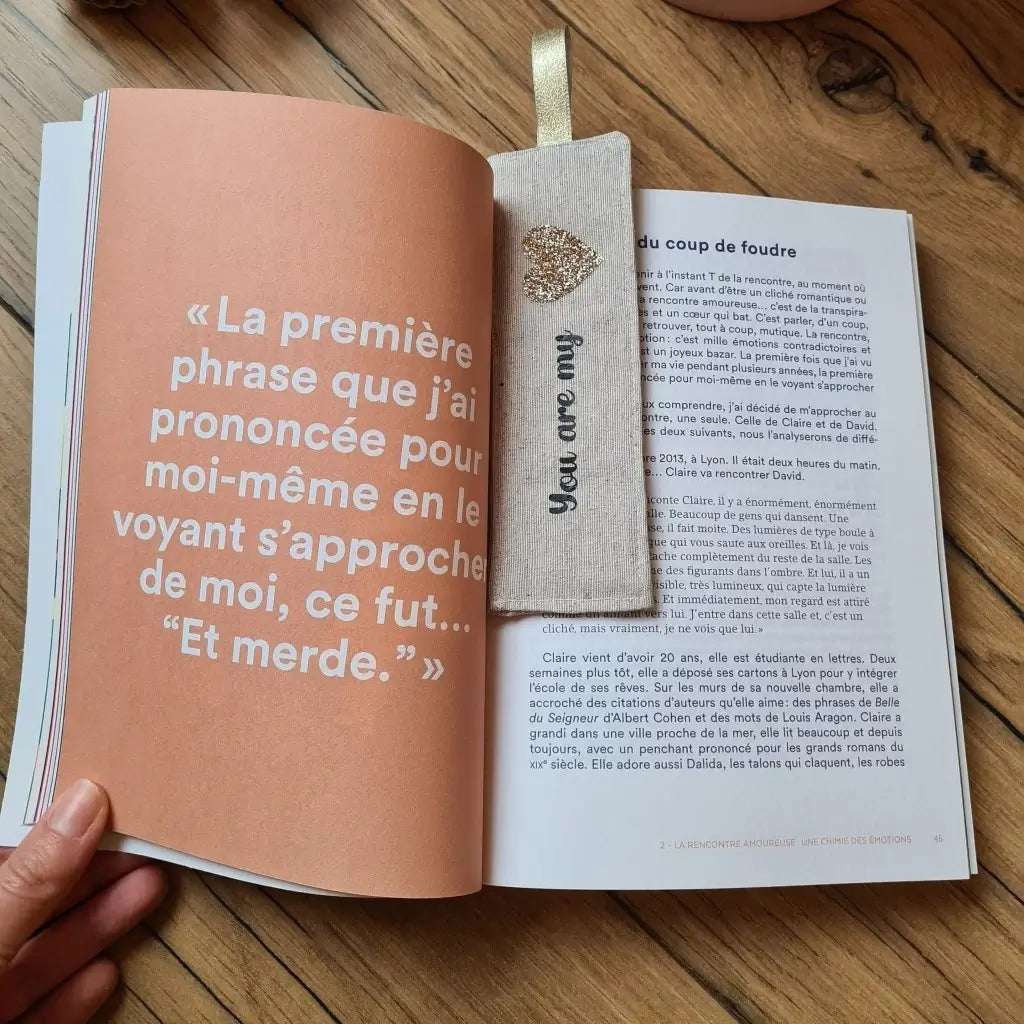 Une main tient un livre ouvert avec un marque-page en tissu glissé entre les pages. Sur ce marque-page en tissu est floquée une inscription personnalisée : "You are my love".