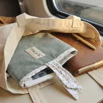 Pochette à livre en velours côtelé bleu clair avec liseuse dans un sac en toile beige.