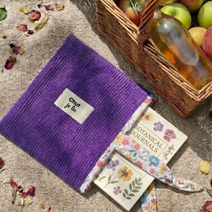 Pochette à livre lavande en velours côtelé lors d'un pique-nique, accessoire de lecture extérieur.