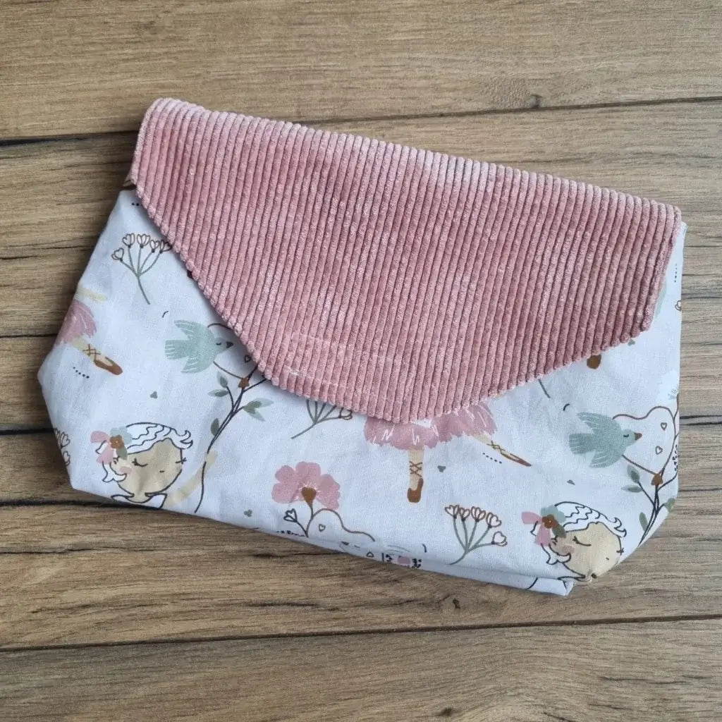 Petite pochette imperméable cousu dans un tissu en coton imprimé au motif danseuse. La pochette dispose d'un rabat en velours côtelé rose.