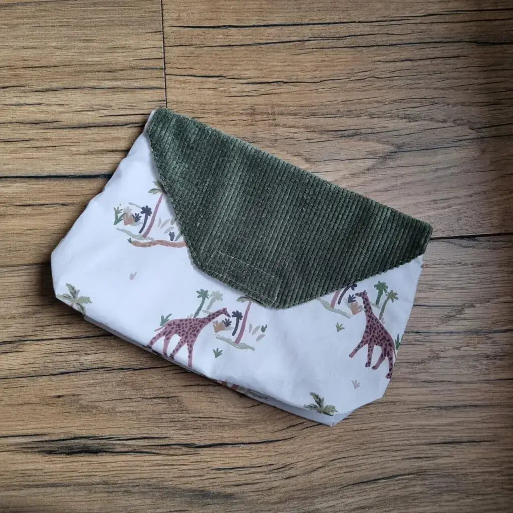 Petite pochette imperméable cousu dans un tissu en coton imprimé au motif jungle. La pochette dispose d'un rabat en velours côtelé vert.