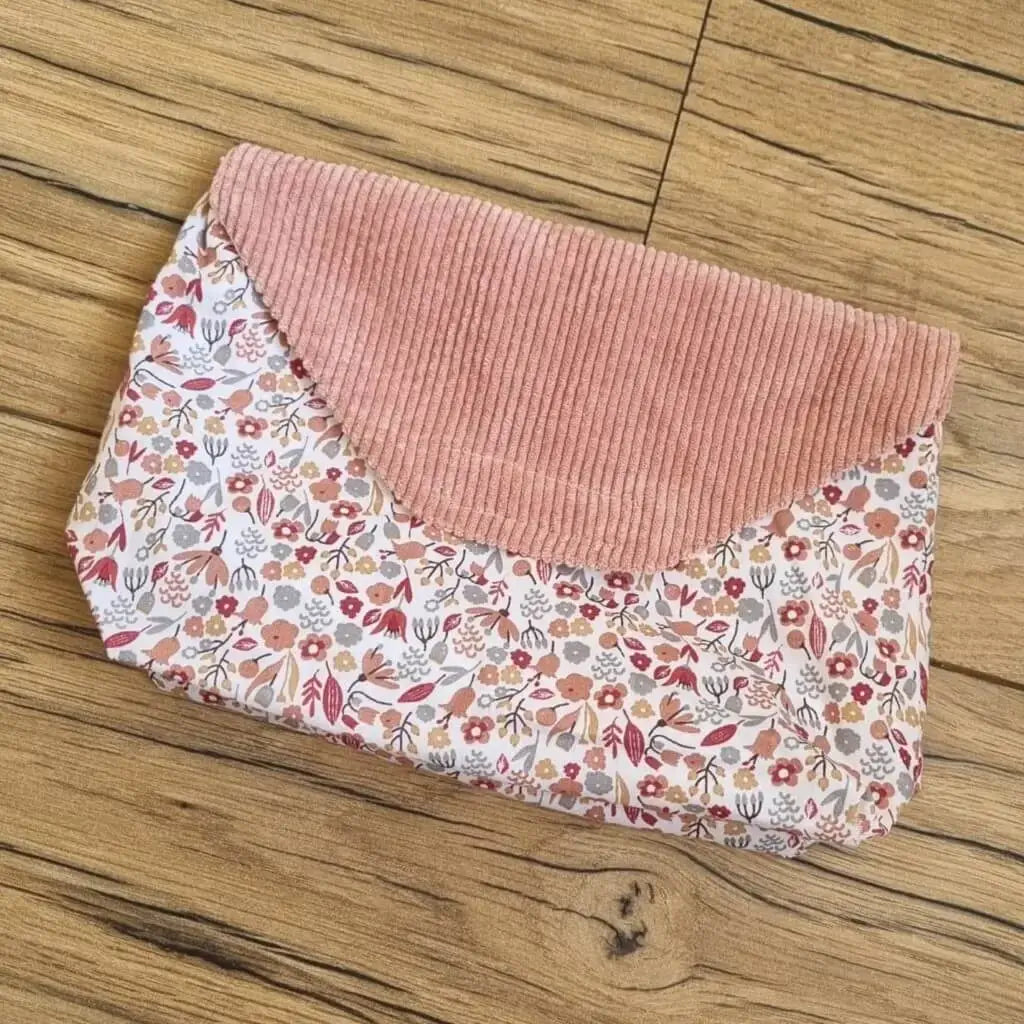 Pochette imperméable composée d'un tissu au motif liberty et d'un rabat en velours côtelé rose.