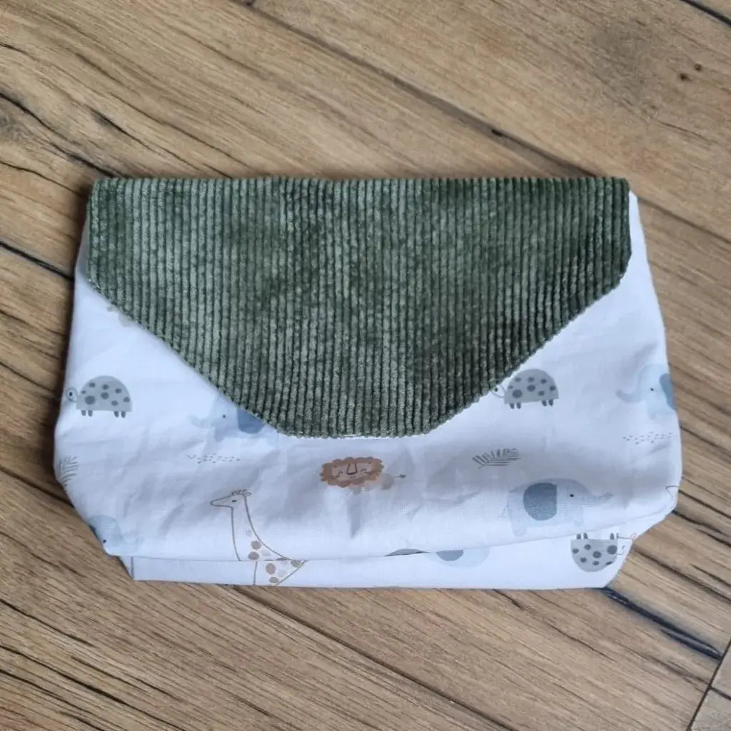 Petite pochette imperméable cousu dans un tissu en coton imprimé au motif savane. La pochette dispose d'un rabat en velours côtelé vert.