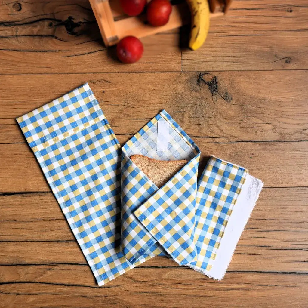 Pochette à sandwich réutilisable en tissu à carreaux bleus, blancs et jaunes, idéale pour emballer un pain de mie ou une demi-baguette de façon écologique et zéro déchet. Accessoire pratique et lavable, parfait pour remplacer le film plastique et transporter son repas de manière saine et durable, tout en apportant une touche vintage et colorée à vos déjeuners nomades.