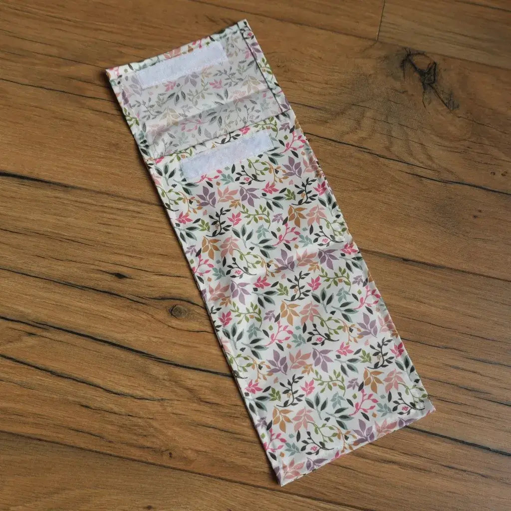 Pochette à sandwich format demi-baguette en tissu enduit motif fleuri pastel, doublée et fermée par bandes velcro, parfaite pour transporter un encas de manière écologique et réutilisable. Alternative zéro déchet aux emballages plastiques pour le déjeuner à l’école, au bureau ou en pique-nique.
