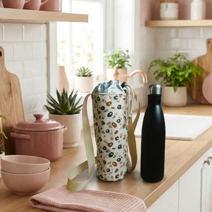 Porte-gourde isotherme motif léopard posé sur un plan de travail en bois dans une cuisine lumineuse et naturelle.