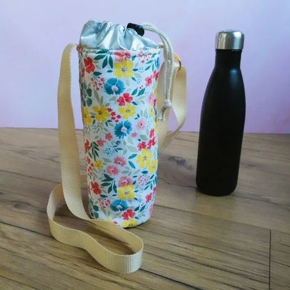 Porte-gourde isotherme en coton enduit motif floral Bridget avec fleurs rouges, jaunes et bandoulière beige.