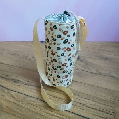 Housse de gourde isotherme imprimé léopard avec bandoulière beige, accessoire de transport pour bouteille réutilisable.