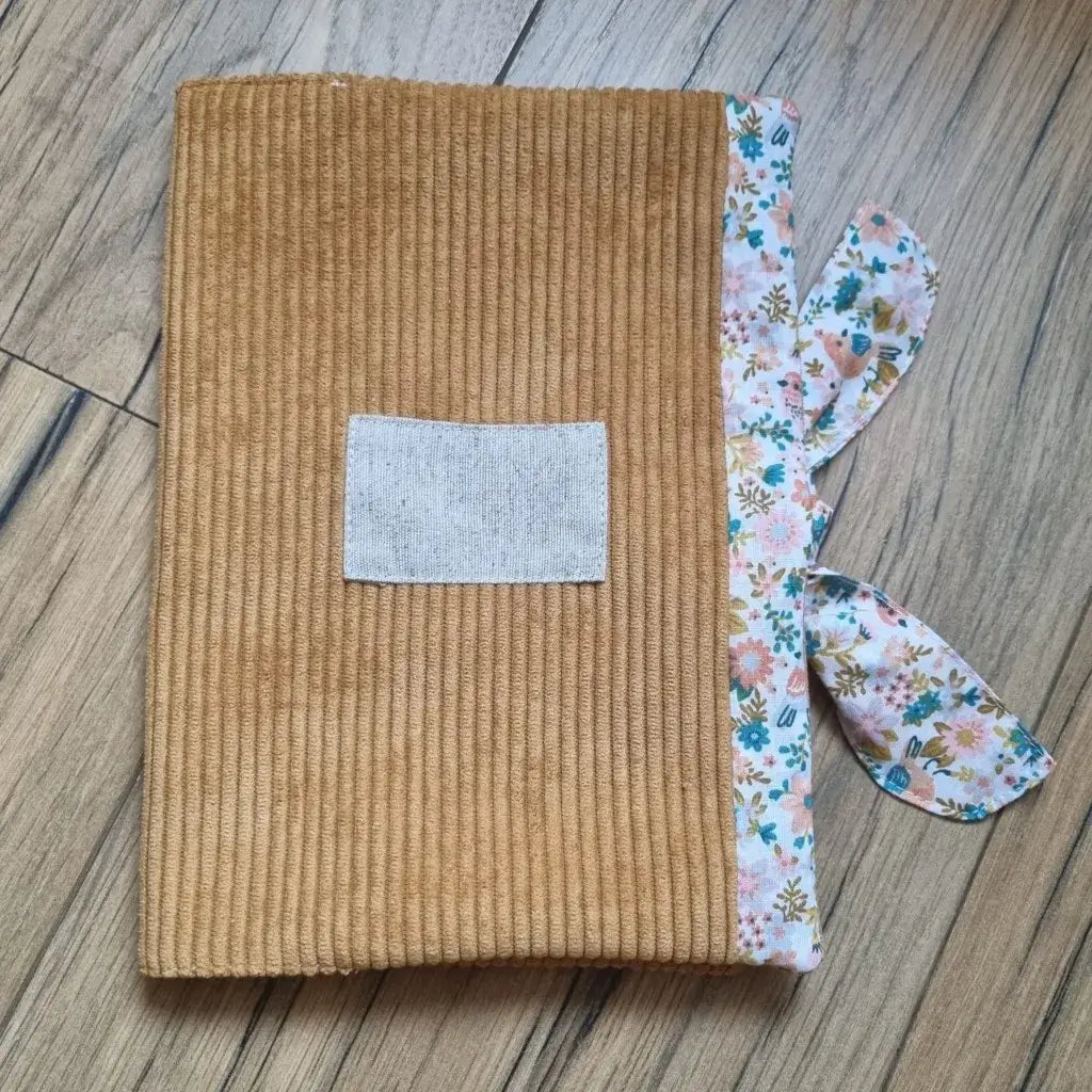 Protège carnet de santé en velours côtelé de coloris jaune. Ce protège carnet de santé se ferme à l'aide d'un ruban en tissu imprimé au motif oiseaux & fleurs. Il est personnalisable avec le prénom de l'enfant floqué sur une petite étiquette en tissu.